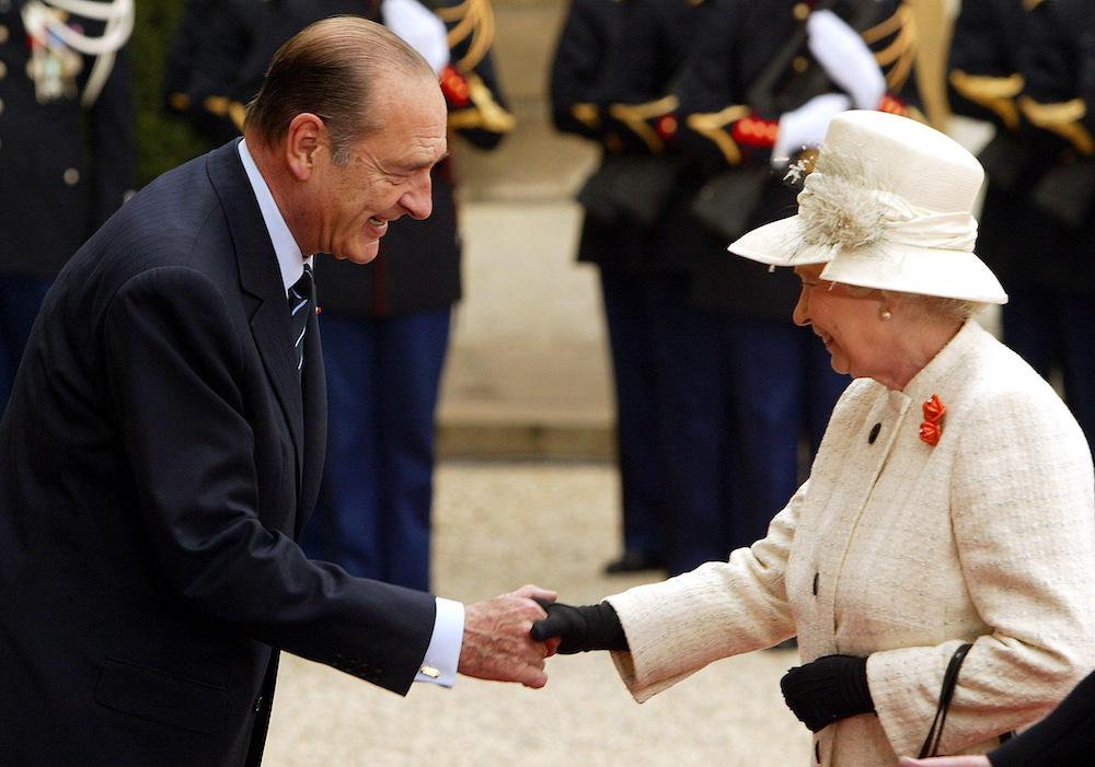 The Queen, wearing a cream hat and suit, shakes hands with French president Jacques Chirac