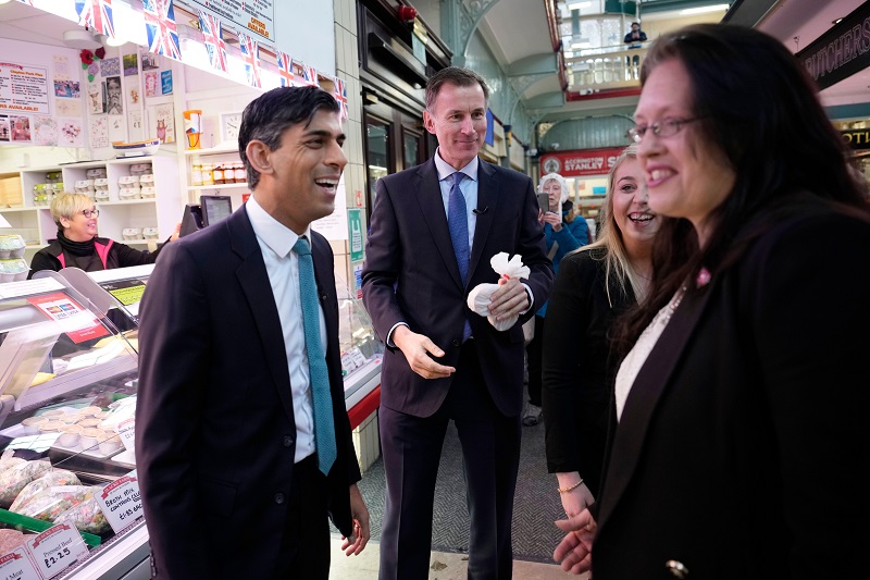 Jeremy Hunt and Rishi Sunak speak to two unidentified women in a market hall