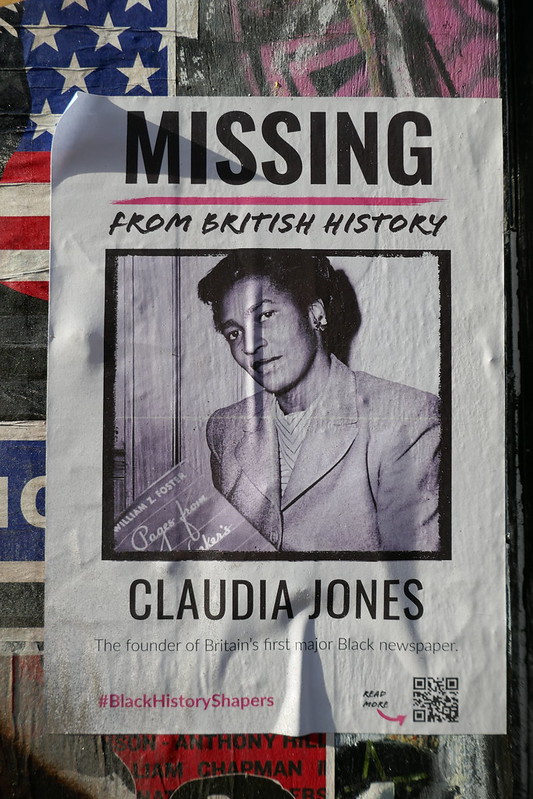 A picture of a poster pasted on a wall with a black and white photo of Claudia Jones. Test on it reads "Missing from British history: Claudia Jones"