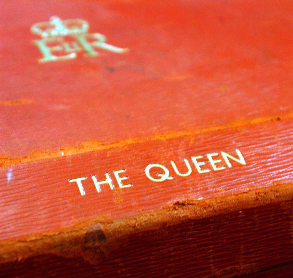 Details on a worn-looking Red Box stamped with 'The Queen'