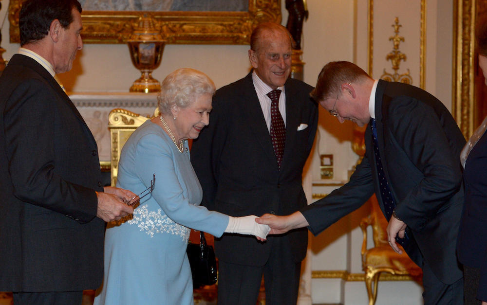 Jeremy Heywood bows while shaking the Queen's hand at the Civil Service Awards, while Prince Philip looks on