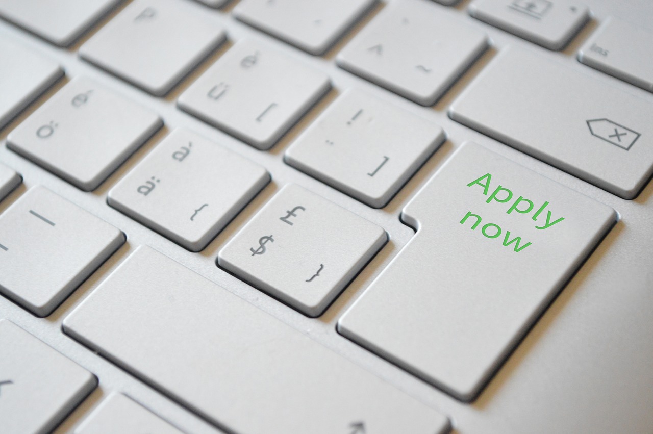 Close-up of a laptop keyboard with return key replaced with one reading "apply now"